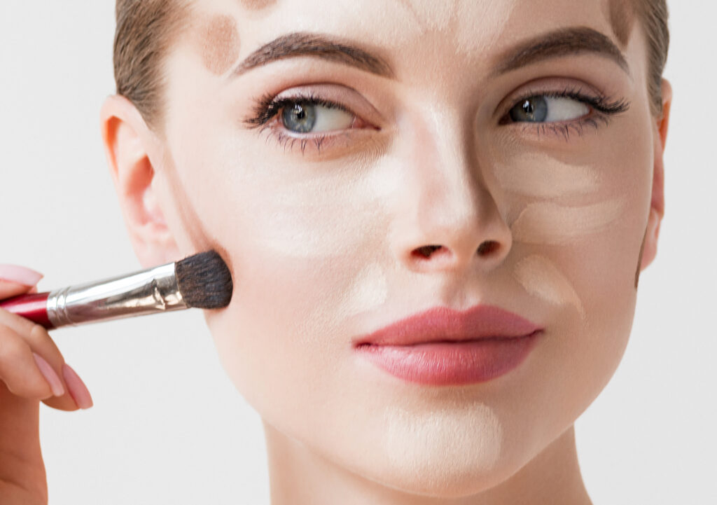 Close-up einer Frau, deren Gesicht mittels Contouring mit einem Pinsel geschminkt wird