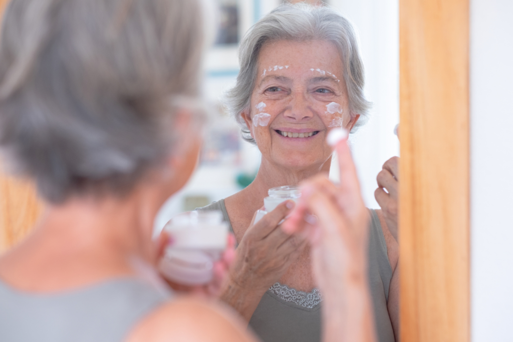 Ältere Dame die Creme auf ihrem Gesicht verteilt