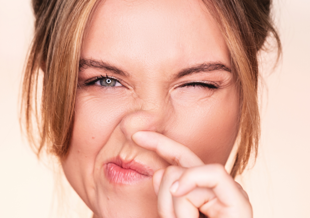 Frau greift sich an Nase