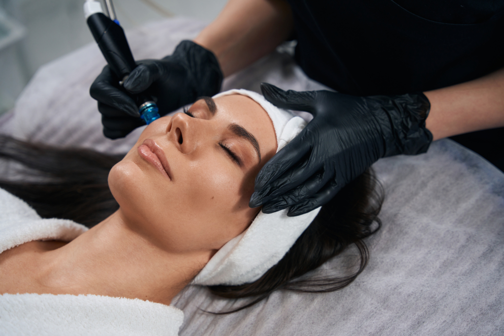Frau liegt auf einer Liege. Hinter ihr zwei Hände mit schwarzen Hygienehandschuhen die einen Stift an ihr Gesicht halten